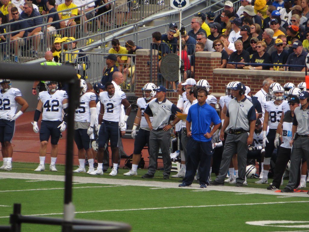 BYU football players stand together with hands on their hips during a game against Michigan.